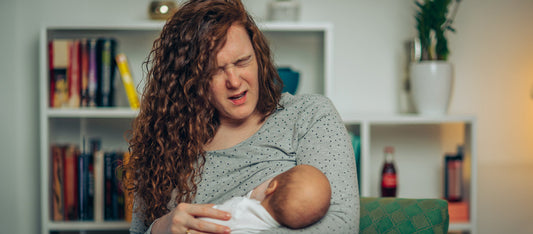 woman wincing in pain from breastfeeding