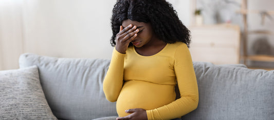 frustrated pregnant black woman sitting on couch