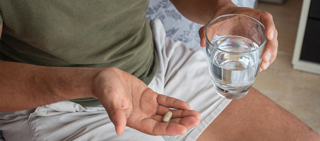 man taking male fertility supplement with water