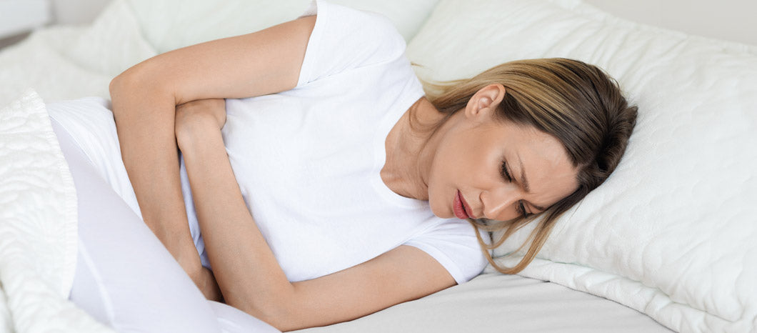 nauseated woman in bed holding her stomach