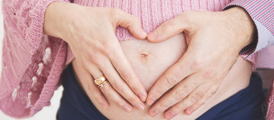 woman making a heart sign on pregnant belly