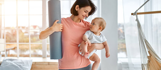 woman holding a yoga mat and baby