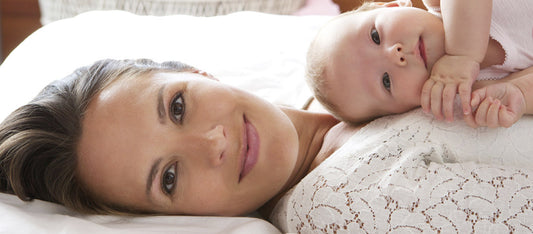 woman laying on bed with baby on chest