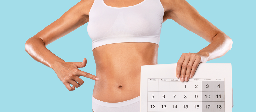 woman holding calendar pointing to stomach