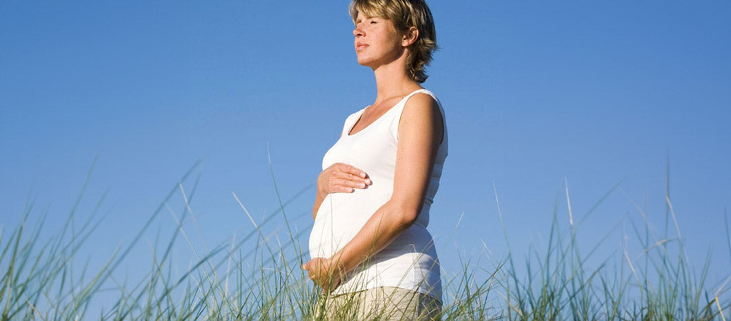 pregnant woman in grassy field getting vitamin D from the sun