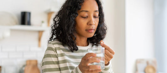 woman taking prenatal vitamin with water